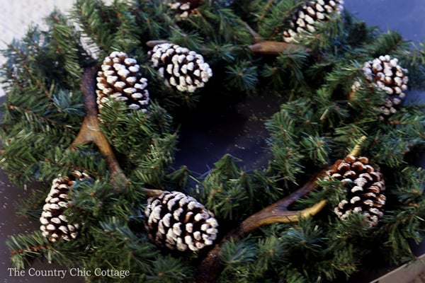 adding pine cones to wreath