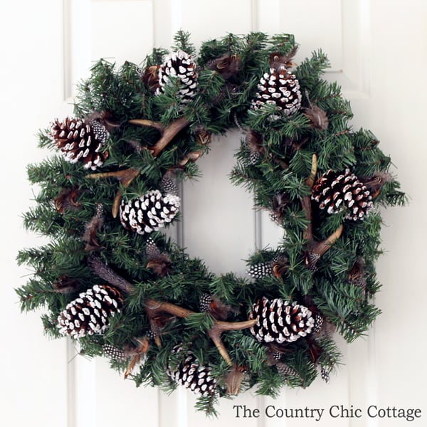 completed antler wreath with feathers, pine cones, and faux deer antlers