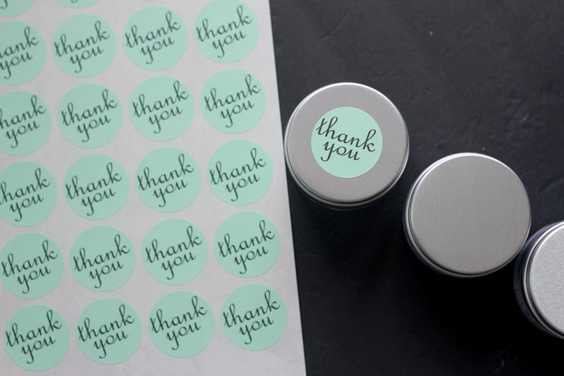 Thank you labels on a sheet next to mason jar lids