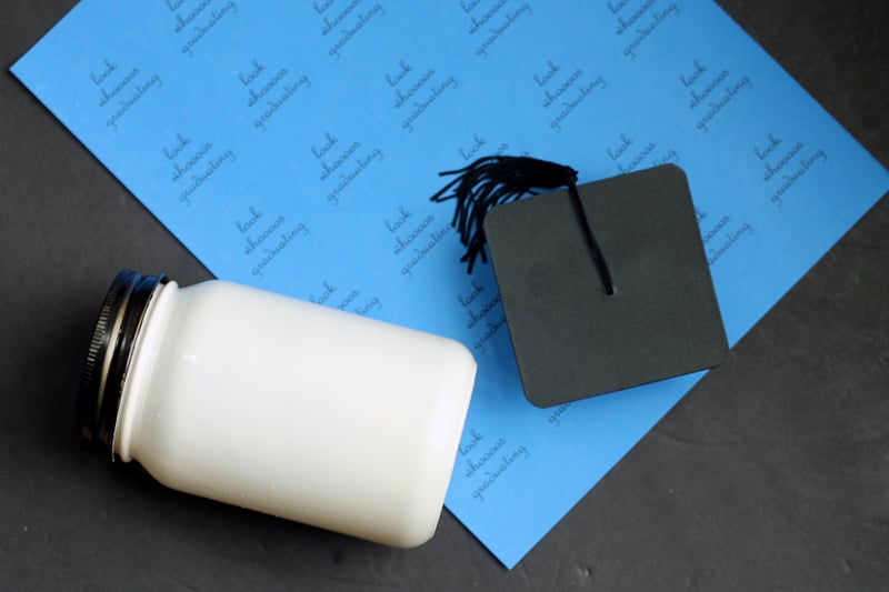 To make this graduation mason jar, a mason jar, a graduation cap, and some printed labels are a few things you need