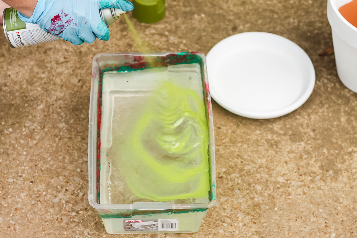 adding spray paint to water in a container