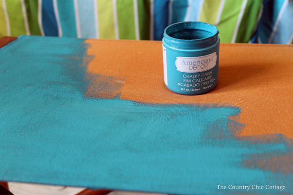 Applying teal paint to orange canvas chair