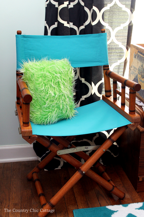 A teal colored canvas chair with green throw pillow