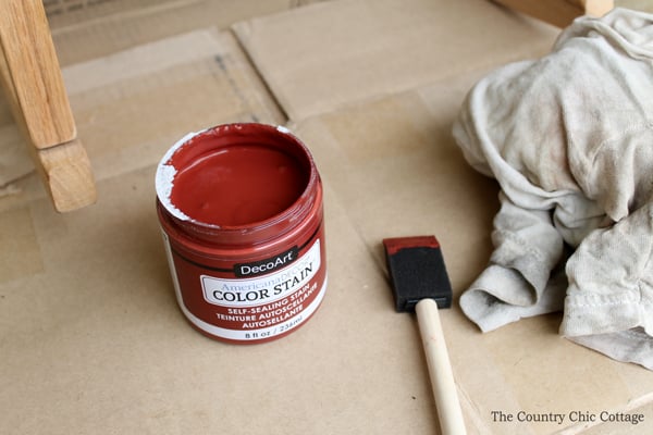 container of red stain and brush