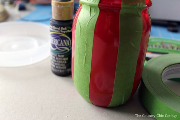mason jar painted red with strips of tape on it