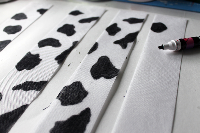 Use a black paint pen to create black spots on white fabric to create cow-themed stripes