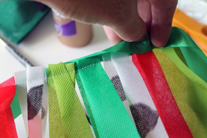 Sewing together the ribbons to make a farm and tractor themed first birthday highchair banner