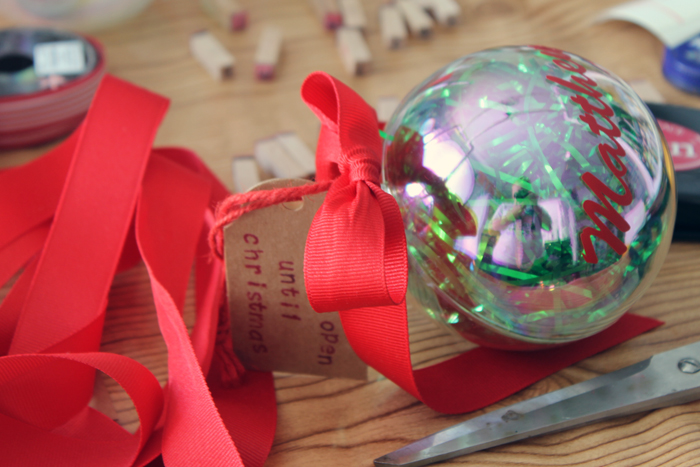 adding a ribbon to a clear ornament filled with money