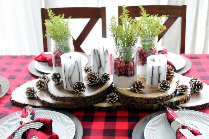 table centerpiece made with wooden rings, candles, christmas mason jars, and pinecones