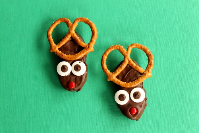 reindeer christmas cookies on green surface with pretzels