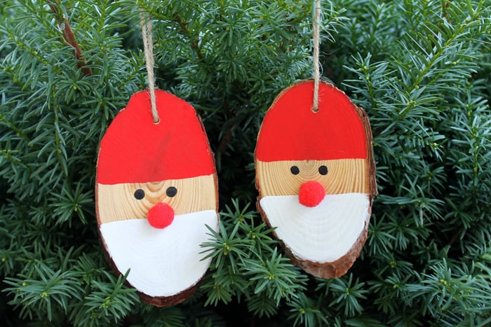 2 Wood Slice Santa Ornaments hanging from a Christmas Tree 