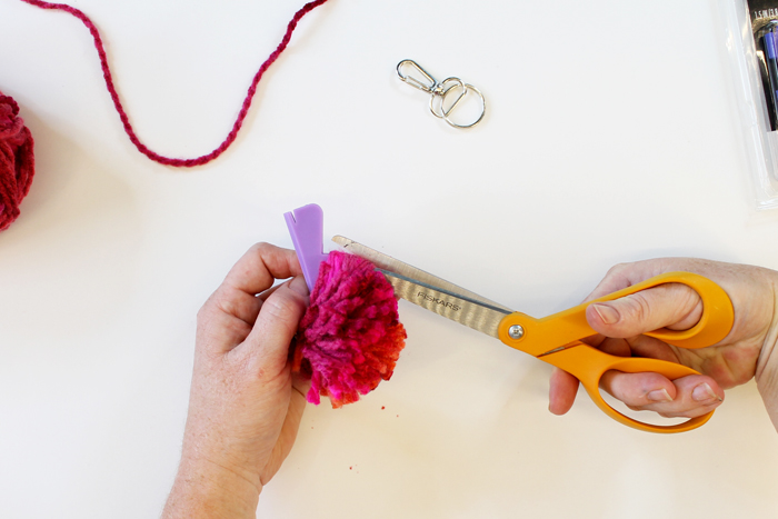 person trimming yarn pom pom