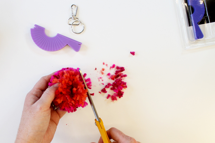 person trimming yarn pom pom