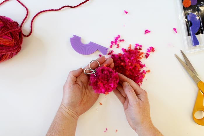 person holding completed yarn pom pom keychain