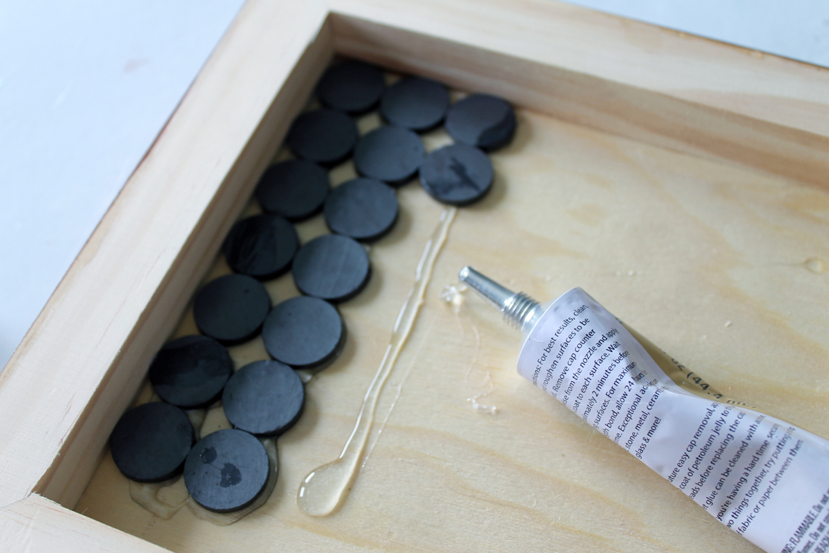 Use a heavy duty adhesive to glue magnets on to the back of the wood panel