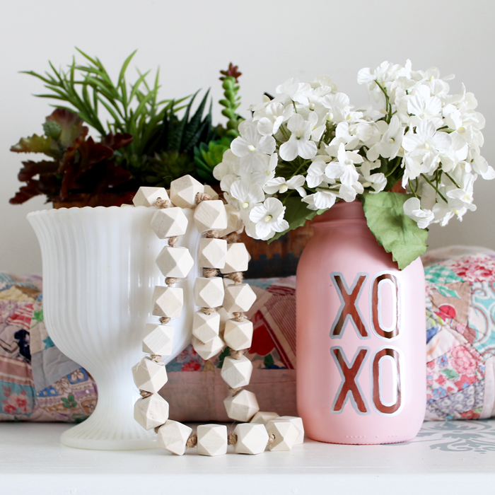 pink mason jar vase with white flowers next to a white flower vase