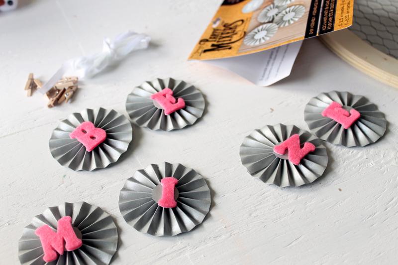 top show of paper rosettes with pink letters attached to them reading "Be Mine"