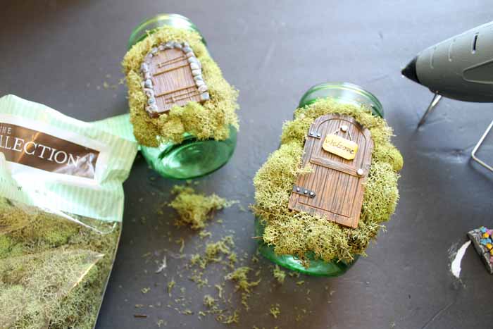 moss and a fairy garden door on a green mason jar