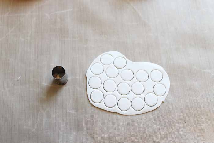 cutting white circles out of a sheet of clay