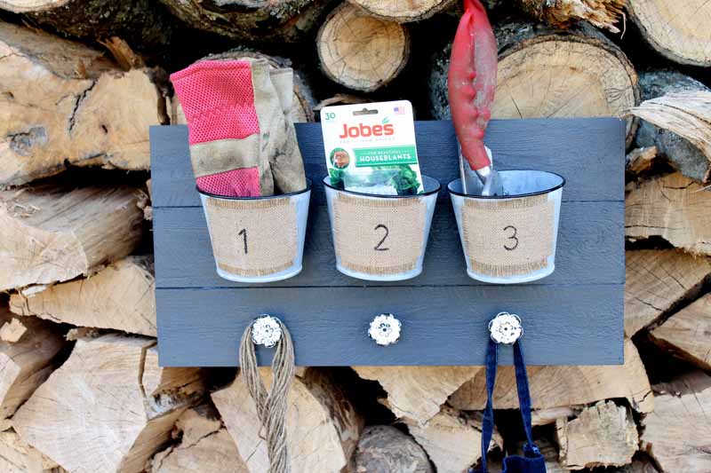 one garden tool storage rack with buckets and numbers on wood