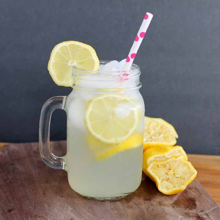 A mason jar glass of fresh-squeezed lemonade with a pink polka-dot straw.