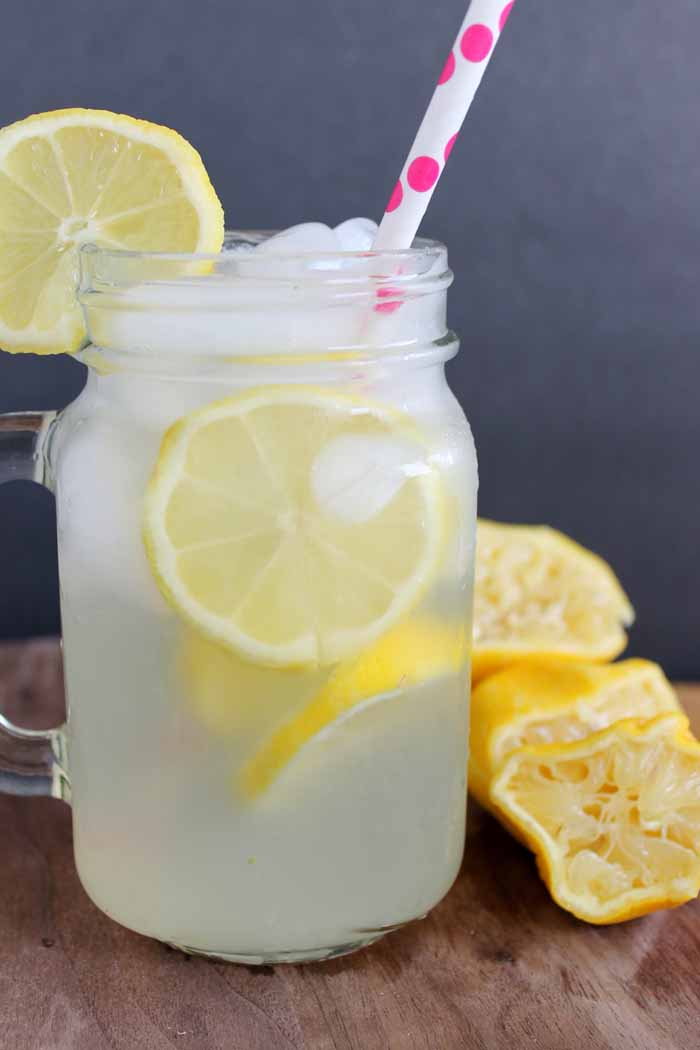 A glass of fresh lemonade with squeezed lemons