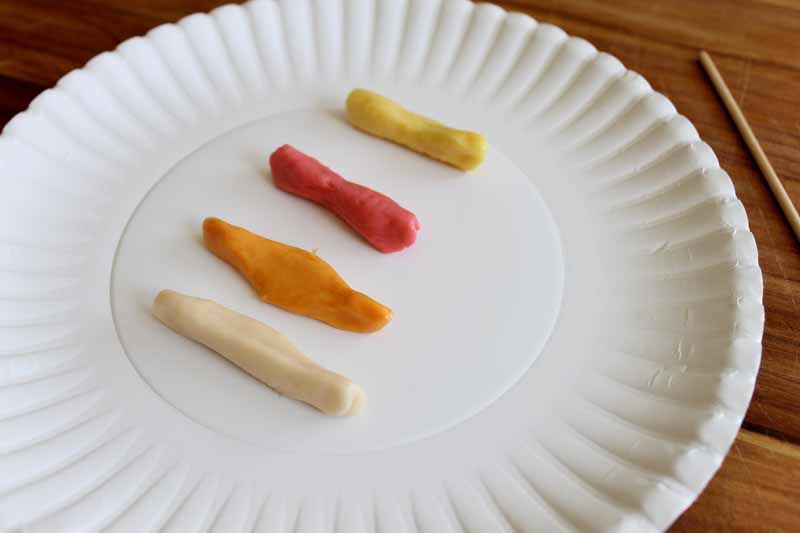 four colored fruit chews unwrapped on white paper plate