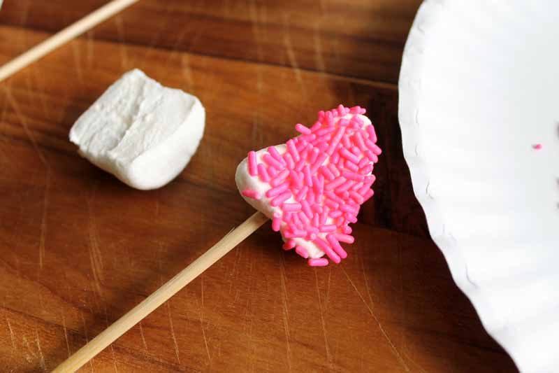marshmallow on wooden skewer covered in pink sprinkles