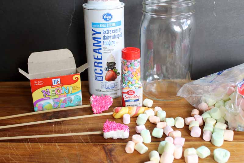 marshmallows, sprinkles and other ingredients for milkshake spread out on wooden table