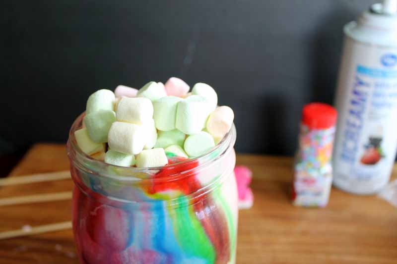 colorful milkshake in mason jar topped with colorful mini marshmallows 