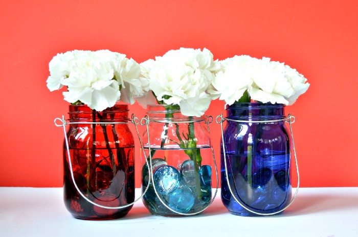 red, clear, and blue mason jar with white flower