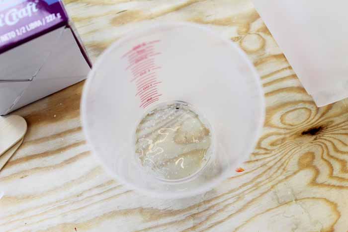 adding hot glue to the bottom of a mixing cup