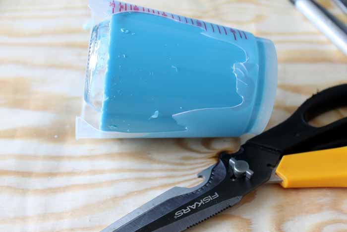 cutting away plastic mixing cup from mold