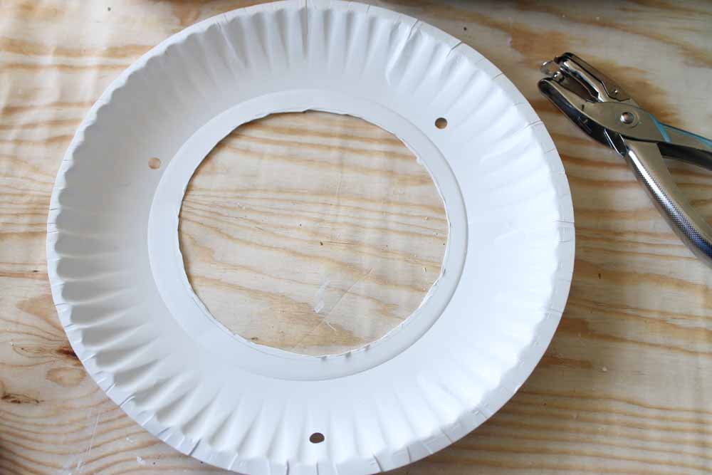 Use a hole punch to punch three holes around the edges of your paper plate kite