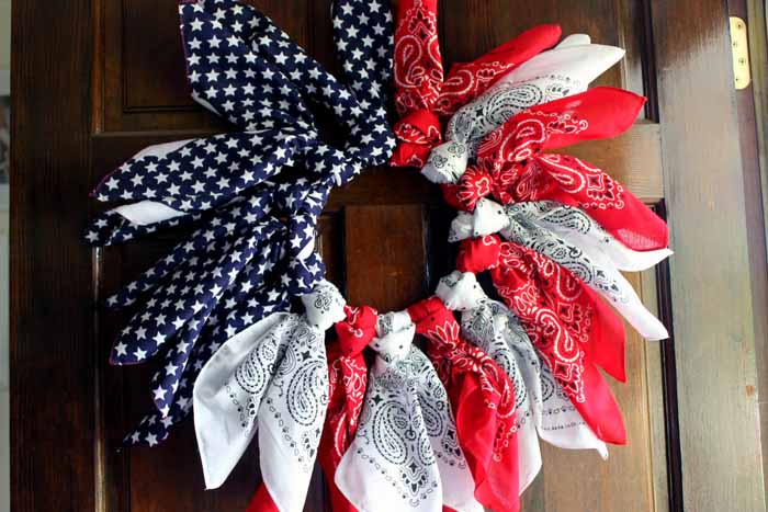 A patriotic wreath made with bandanas hanging on a front door.