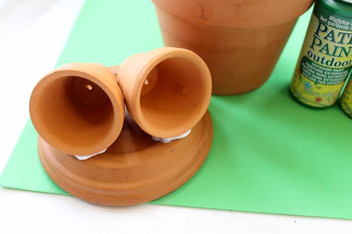 Attach two small pots to the lid of the larger pot to create the frog's eyes