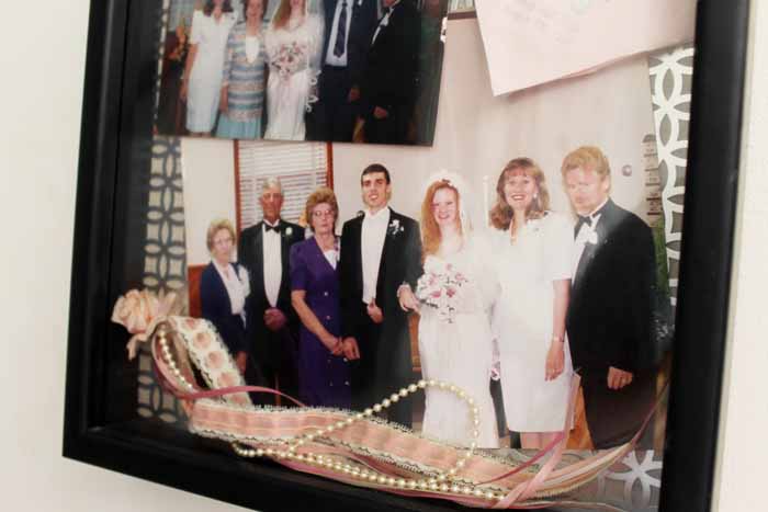 Photos, a napkin, and a garter displayed in a frame. 