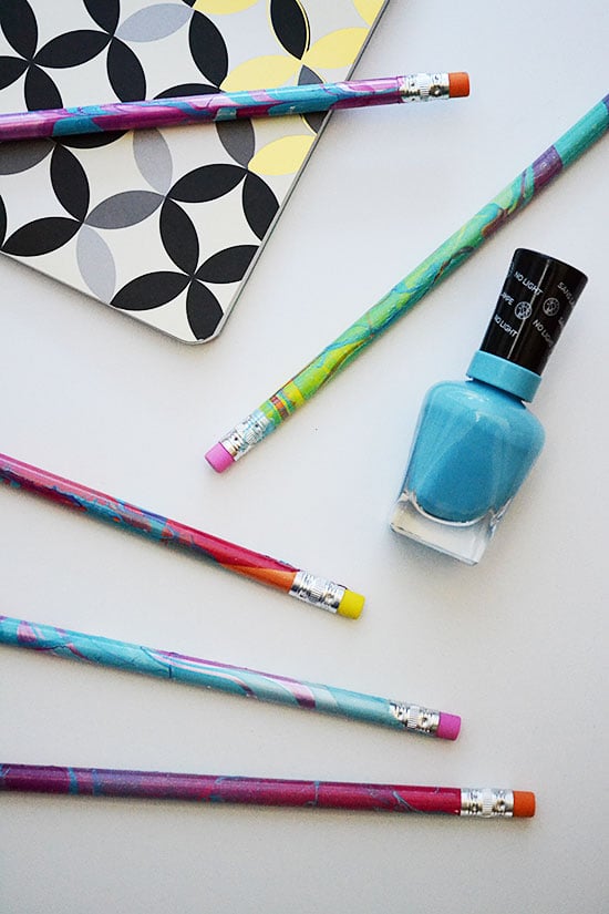 pencils and nail polish with a file folder on white backdrop