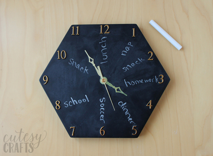 chalkboard clock on a wooden backdrop with a piece of chalk