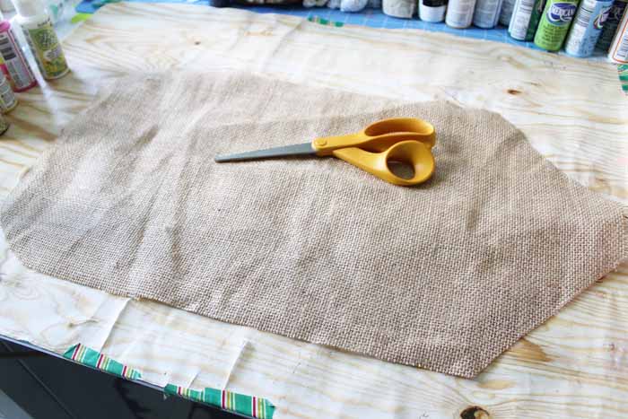 piece of burlap with scissors on top on unfinished wood