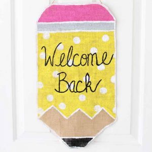 painted burlap pencil wall hanging on white door that says welcome back