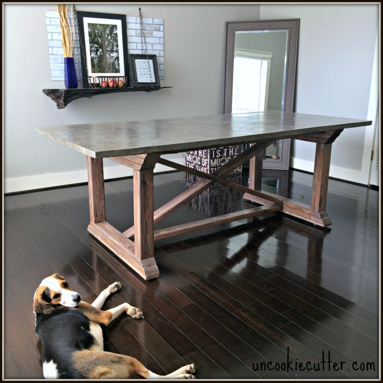 concrete table top  with x supports, wood floor with dog
