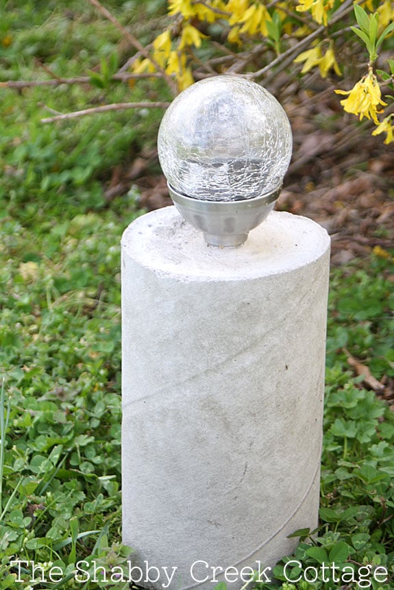 picture of a concrete light post in front of greenery