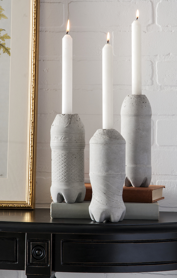 concrete candle stick holders on top of books in front of a white brick wall