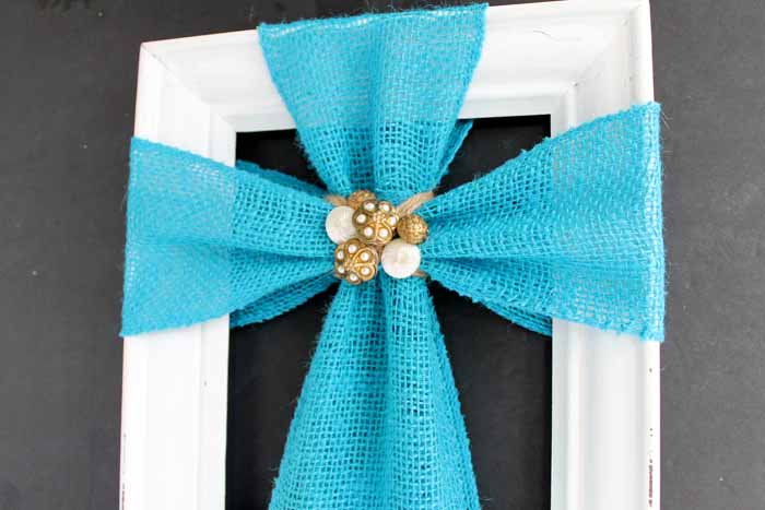 Completed burlap cross craft. Blue burlap cross design on white frame with gold brooch