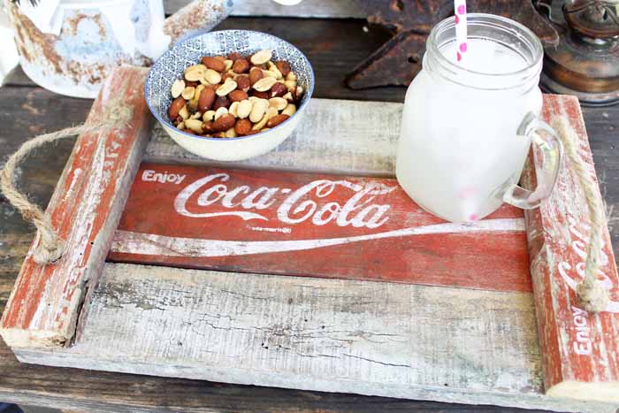 A close up of glass of milk, mixed nuts on a diy farmhouse tray