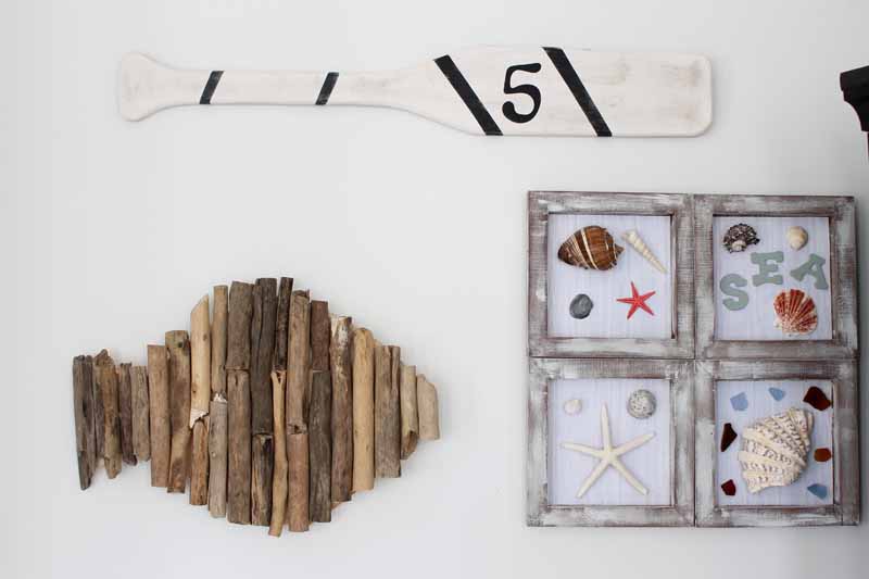 driftwood fish, shell framed art and an oar on a white gallery wall