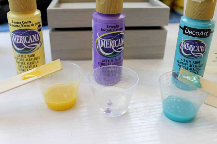 plastic cups with yellow and turquoise in front of a purple tube of craft paint