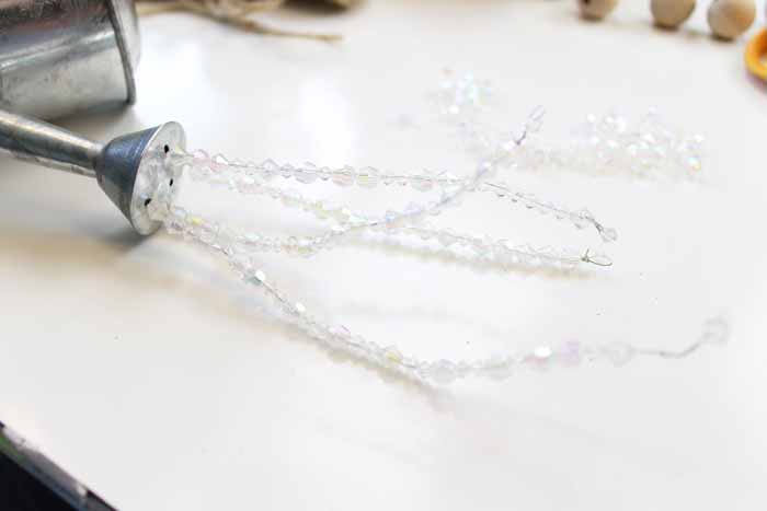 strings of clear beads flowing from galvanized watering can