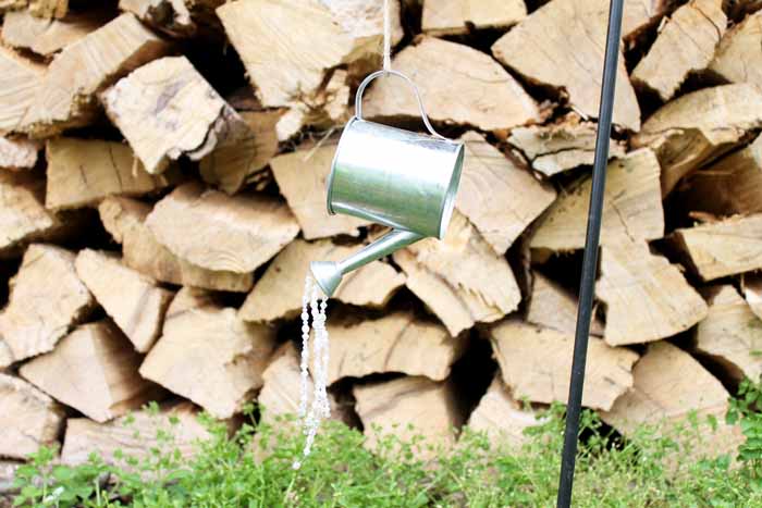 hanging galvanized watering can with strings of beads